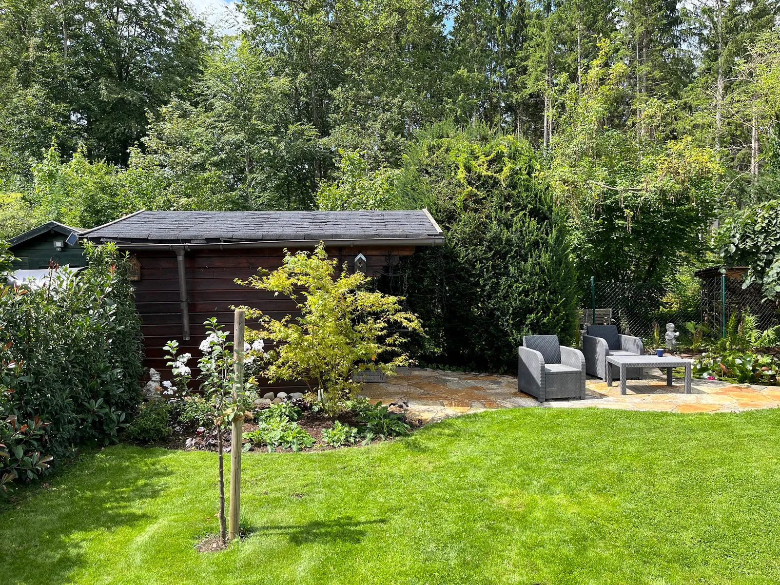 Gartenrasen mit Terrasse und Gartenhaus im Grünen